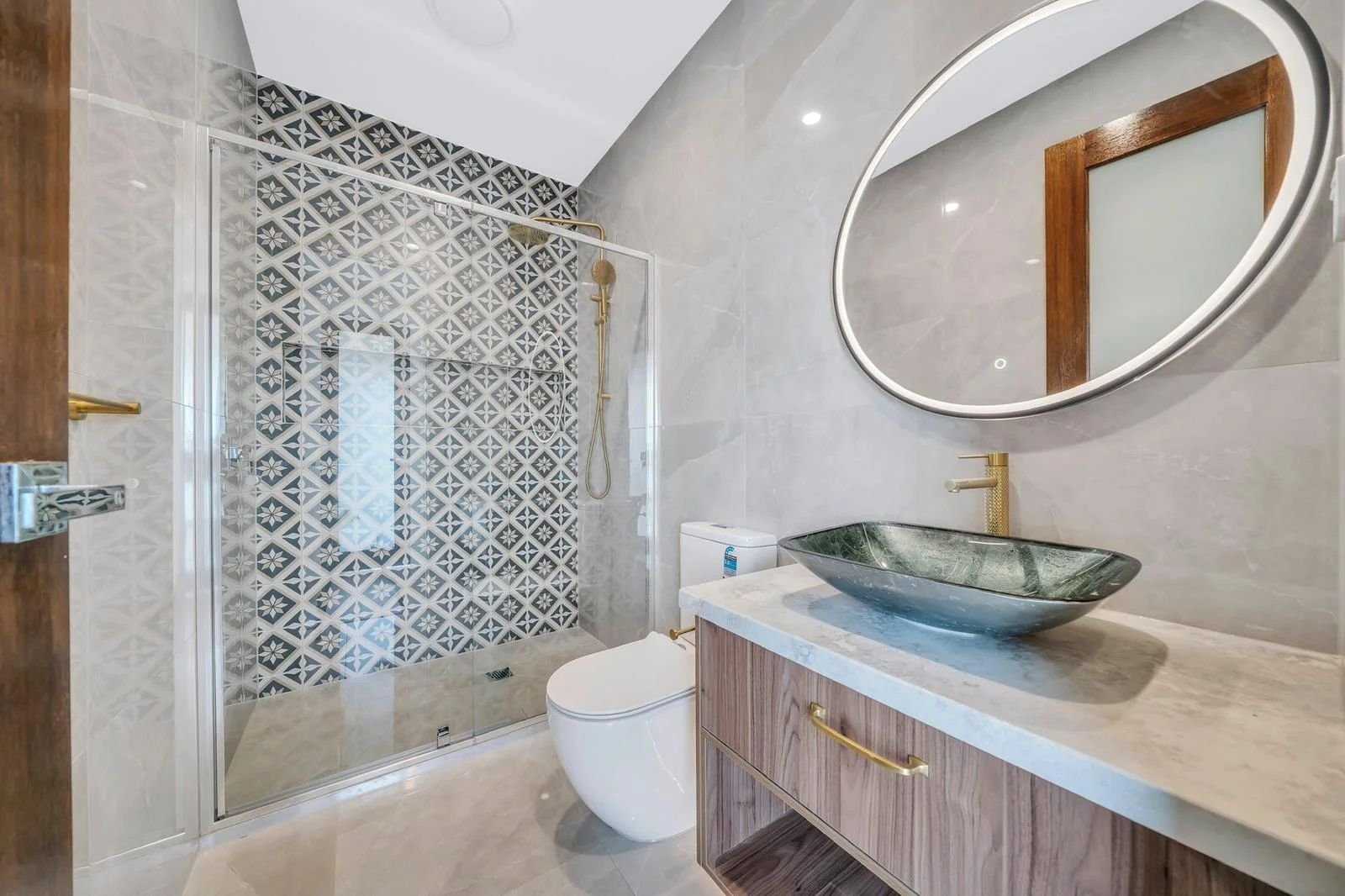 Bathroom with patterned feature tiles and round mirror