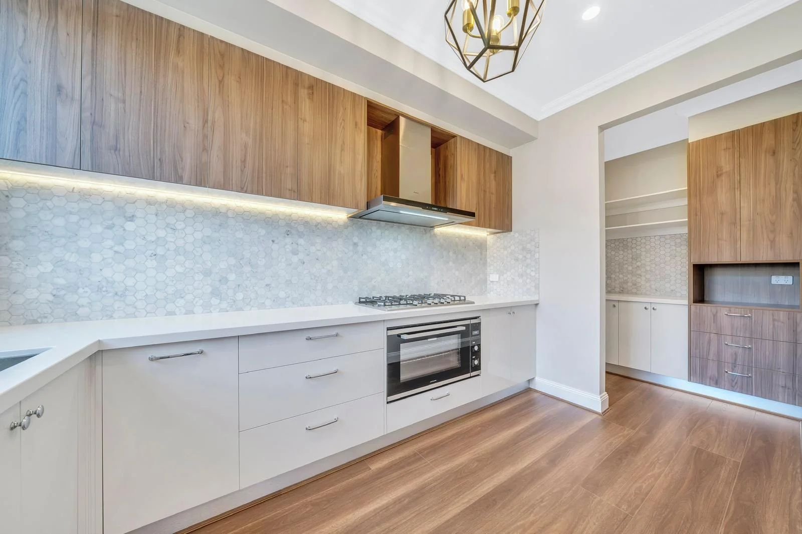 Kitchen with timber overhead cabinets and hexagon splashback